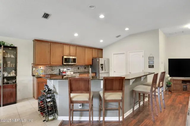 a kitchen with stainless steel appliances kitchen island granite countertop a table and chairs in it