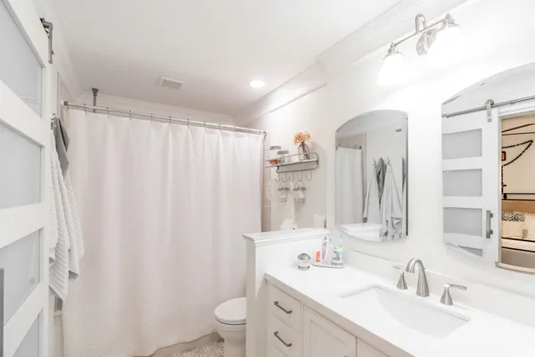 a bathroom with double vanity sink a toilet a mirror and shower curtain