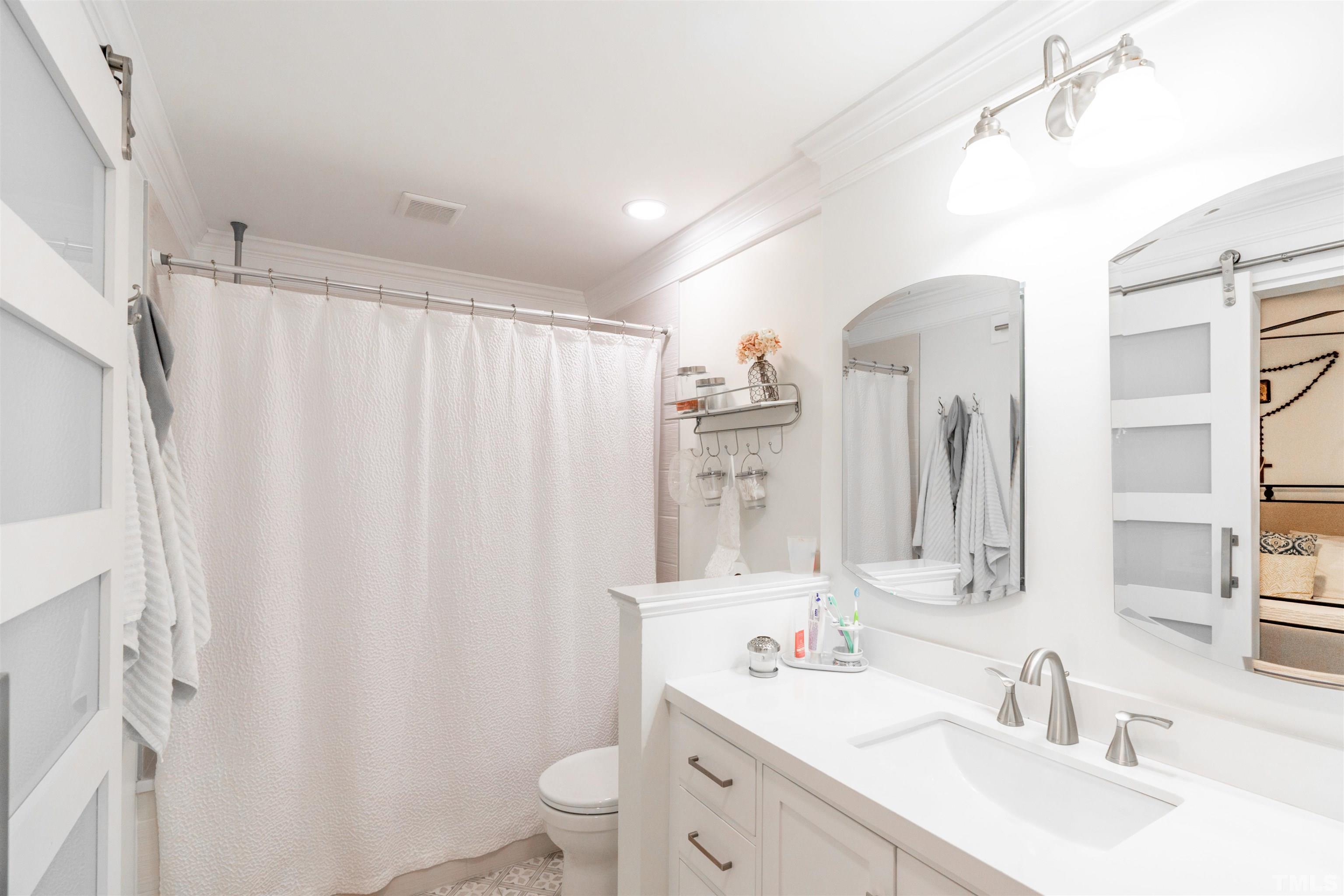 7304 Ray Road Raleigh, NC 27613 - Photo 16 of 30 a bathroom with double vanity sink a toilet a mirror and shower curtain