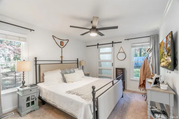 a bedroom with a bed a flat screen tv and a dresser with the potted plant