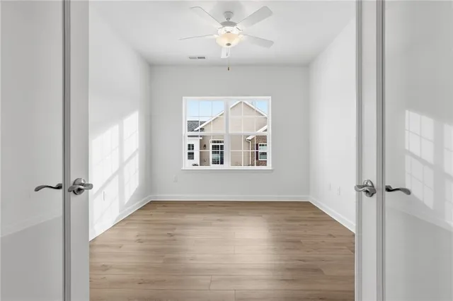 an empty room with windows and a chandelier fan