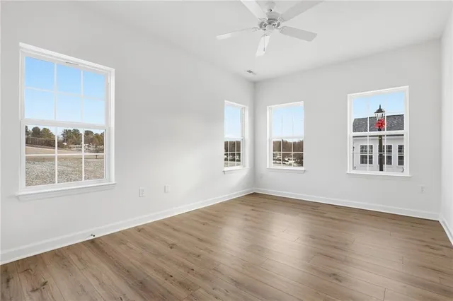 a view of an empty room with wooden floor and windows