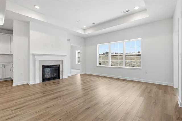 an empty room with wooden floor fireplace and windows