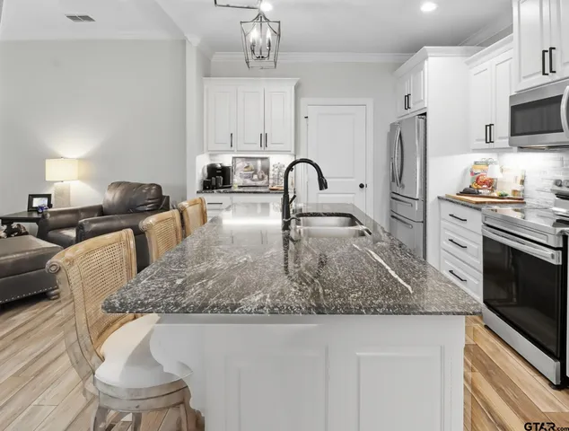 a kitchen with stainless steel appliances granite countertop a sink a stove and refrigerator