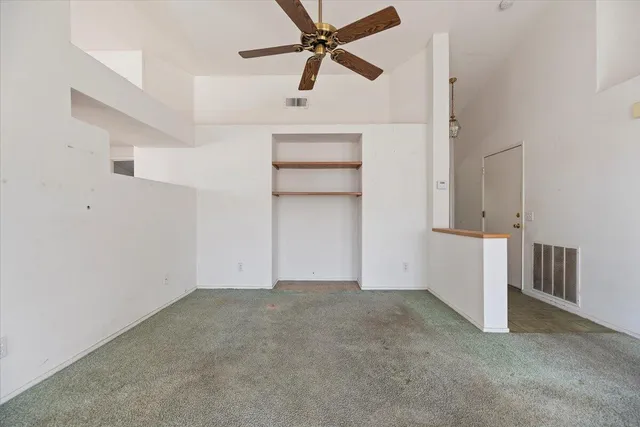an empty room with closet and a ceiling fan