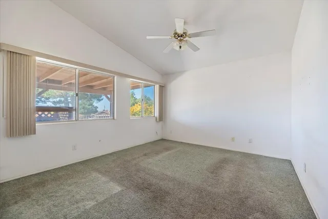 an empty room with windows and ceiling fan