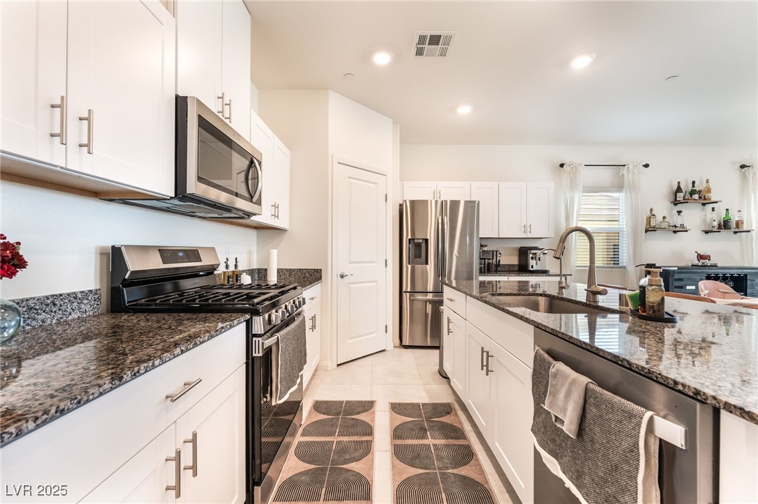 10947 Artisan Ranch Avenue Las Vegas, NV 89166 - Photo 13 of 39 Kitchen with appliances with stainless steel finishes, dark stone countertops, white cabinetry, light tile patterned flooring, and recessed lighting