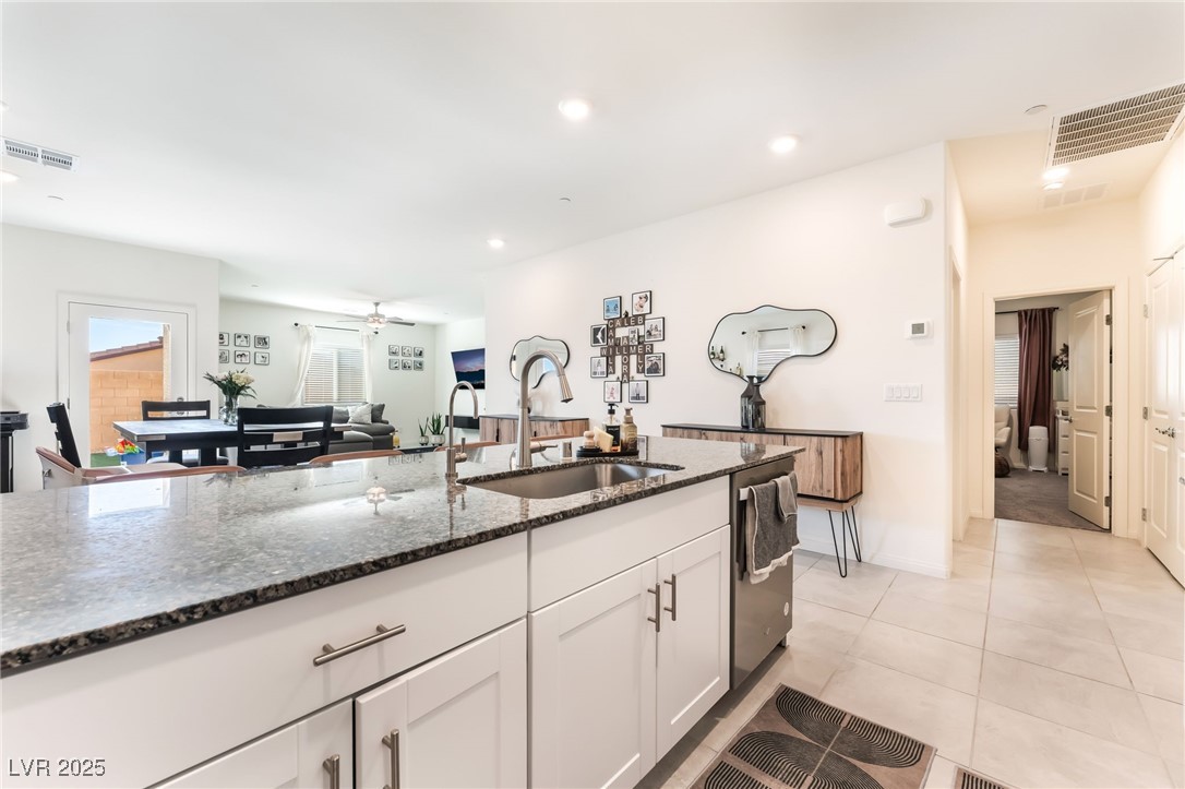 10947 Artisan Ranch Avenue Las Vegas, NV 89166 - Photo 38 of 39 Kitchen featuring dark stone countertops, white cabinetry, ceiling fan, open floor plan, and stainless steel dishwasher
