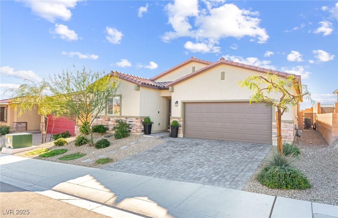 10947 Artisan Ranch Avenue Las Vegas, NV 89166 - Photo 2 of 39 Mediterranean / spanish house featuring stone siding, decorative driveway, stucco siding, an attached garage, and a tile roof