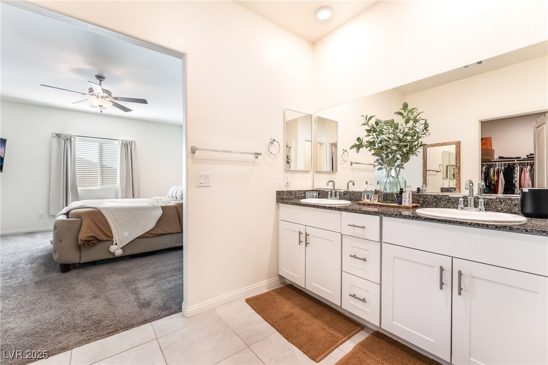 10947 Artisan Ranch Avenue Las Vegas, NV 89166 - Photo 19 of 39 Ensuite bathroom with double vanity, light colored carpet, a walk in closet, light tile patterned floors, and ceiling fan