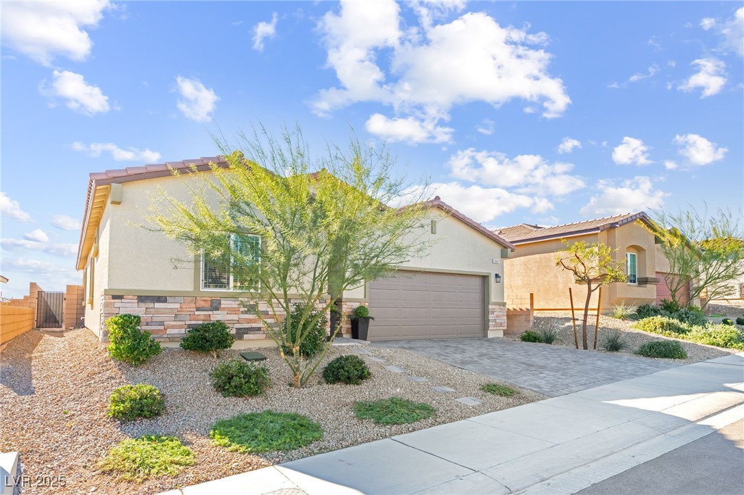 10947 Artisan Ranch Avenue Las Vegas, NV 89166 - Photo 3 of 39 Mediterranean / spanish home with stone siding, stucco siding, decorative driveway, a garage, and a tiled roof