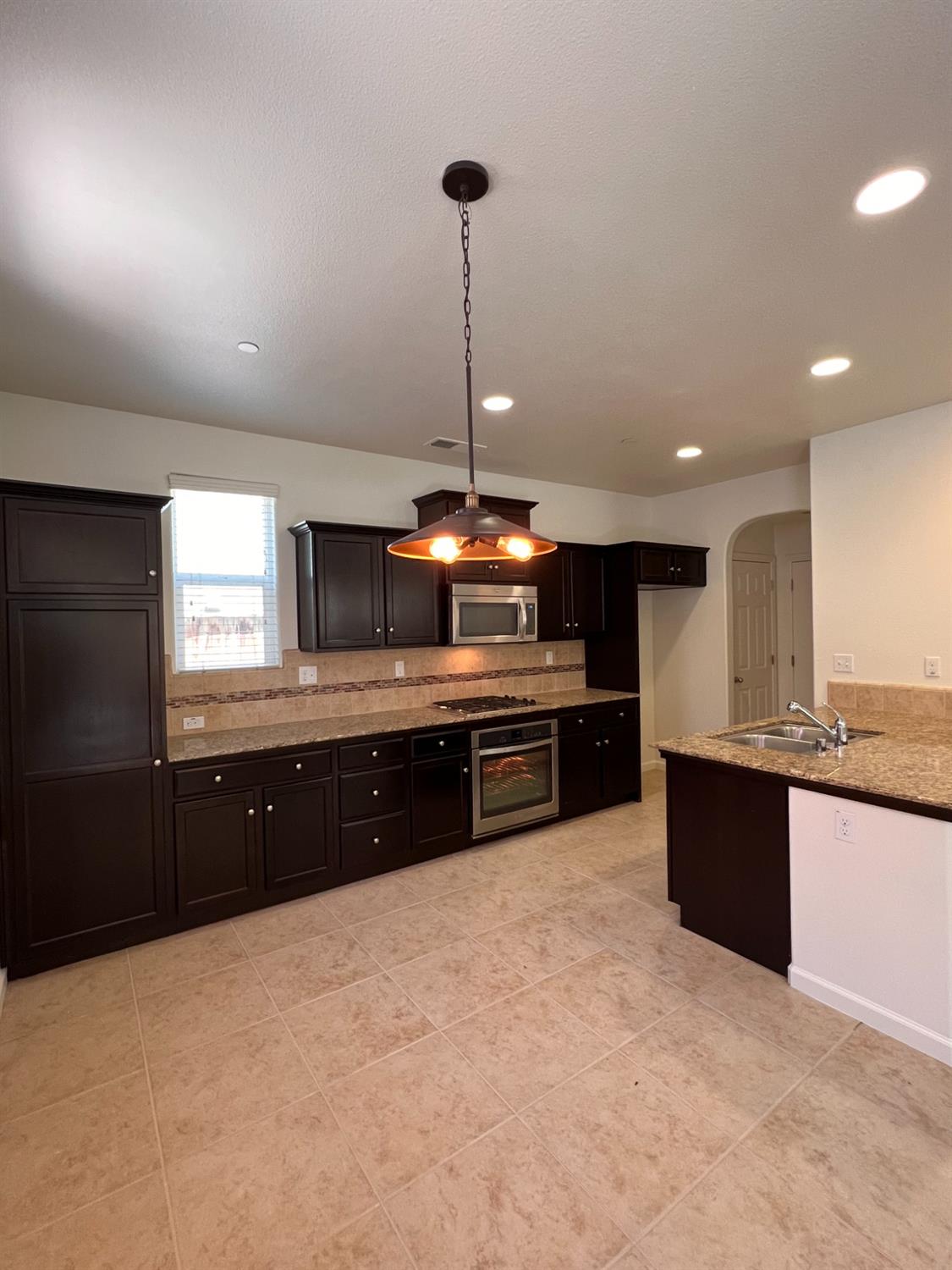 1504 Mosaic Way Clovis, CA 93619 - Photo 11 of 34 a large kitchen with stainless steel appliances granite countertop a refrigerator a sink and a stove