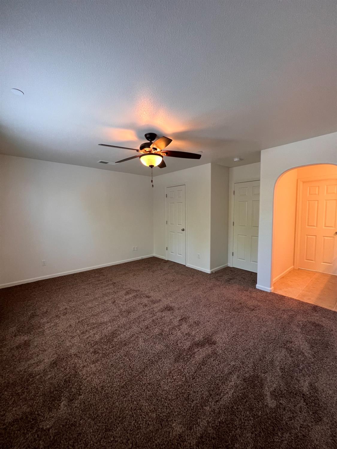 1504 Mosaic Way Clovis, CA 93619 - Photo 24 of 34 an empty room with a chandelier fan and windows