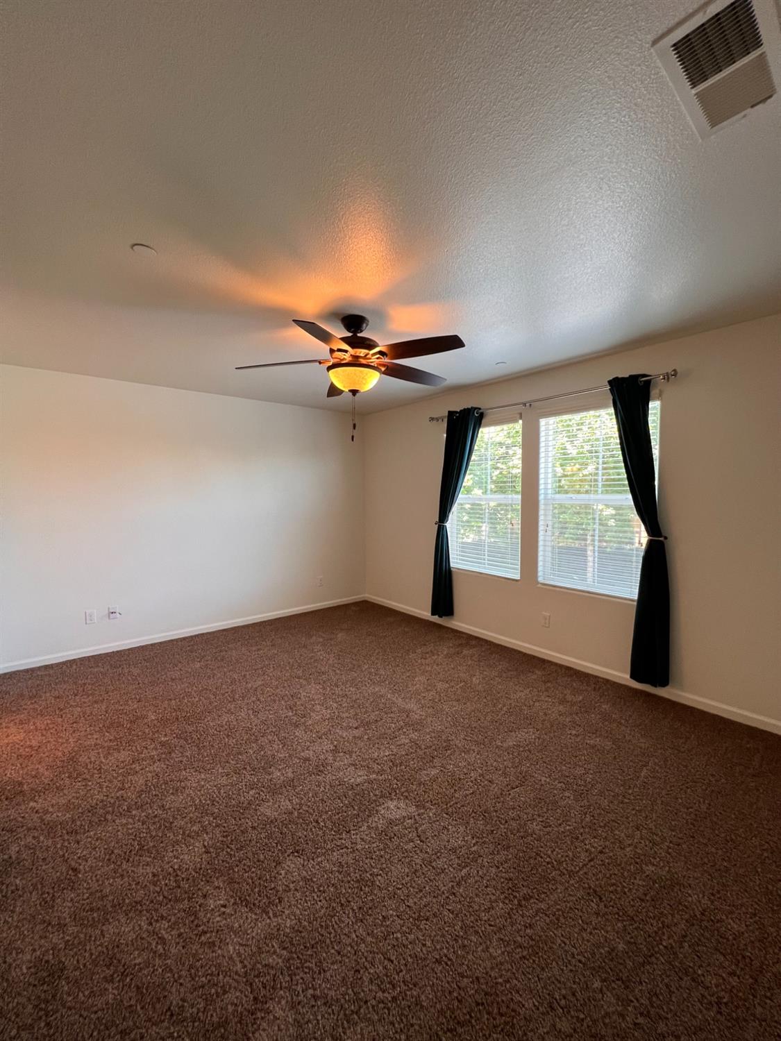 1504 Mosaic Way Clovis, CA 93619 - Photo 25 of 34 an empty room with windows and chandelier fan