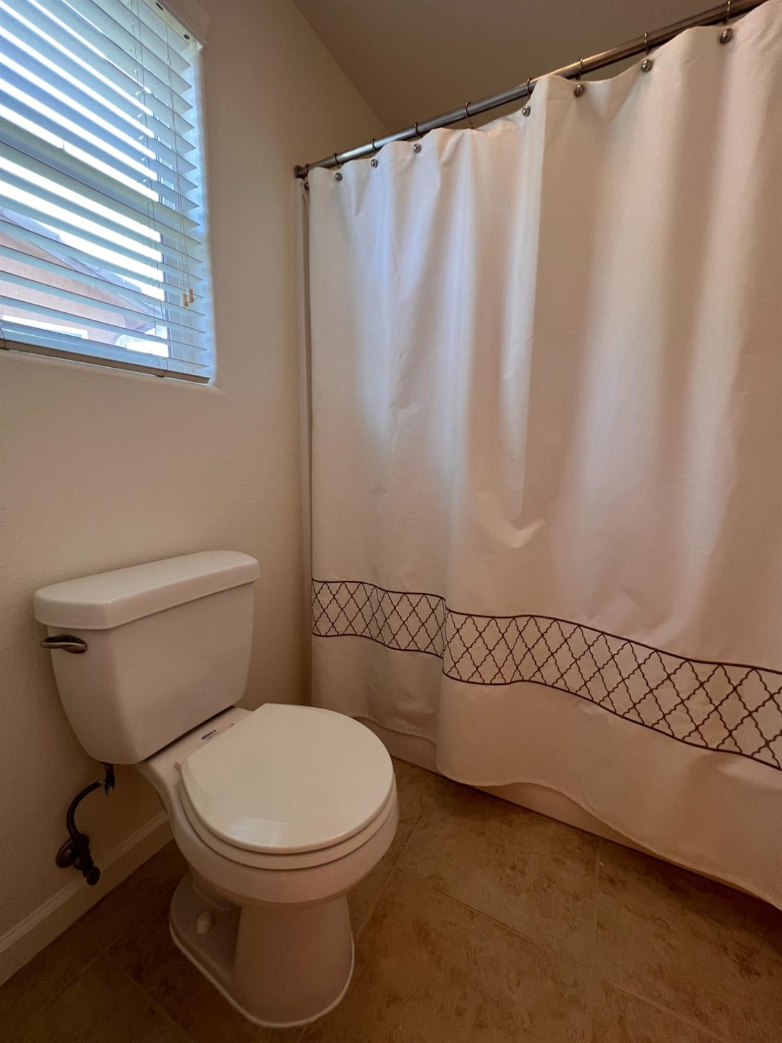 1504 Mosaic Way Clovis, CA 93619 - Photo 31 of 34 a white toilet sitting next to a shower curtain