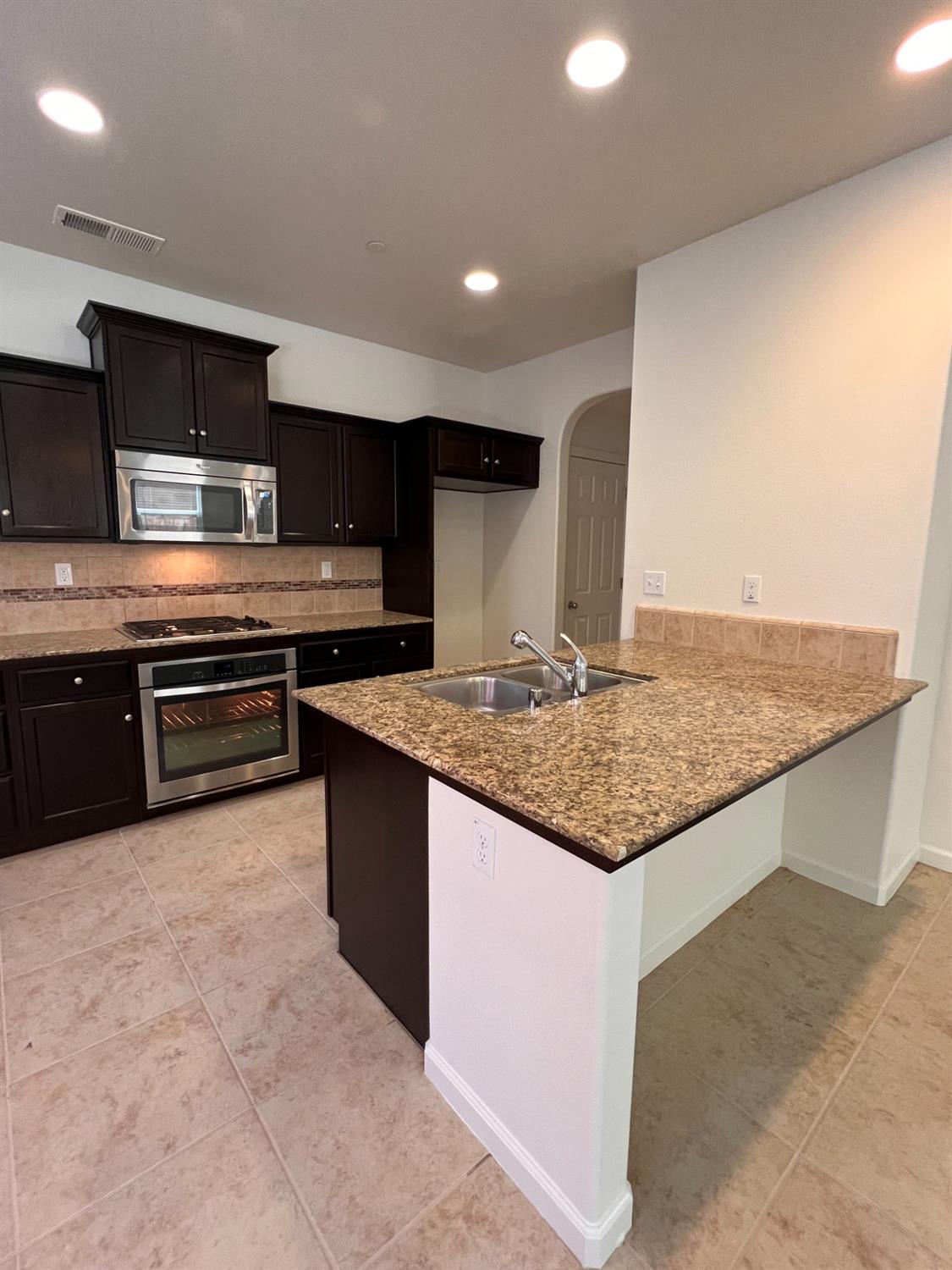 1504 Mosaic Way Clovis, CA 93619 - Photo 7 of 34 a kitchen with stainless steel appliances granite countertop a sink and a stove