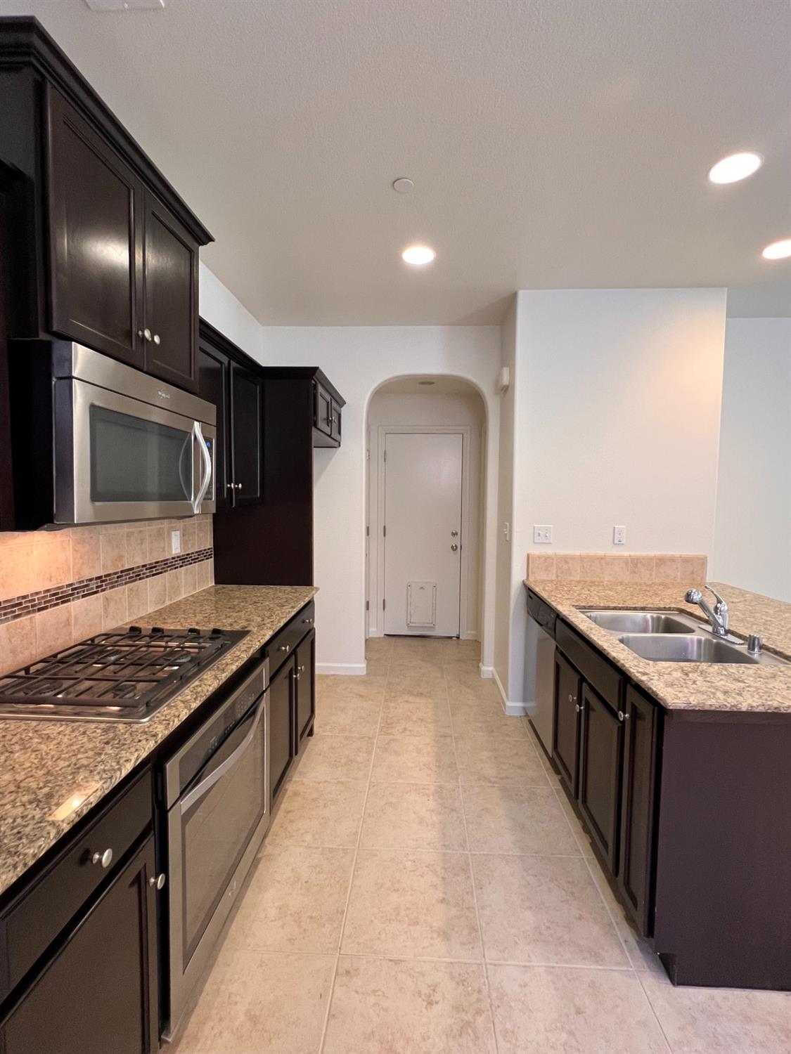 1504 Mosaic Way Clovis, CA 93619 - Photo 8 of 34 a kitchen with stainless steel appliances granite countertop a stove a sink and a refrigerator