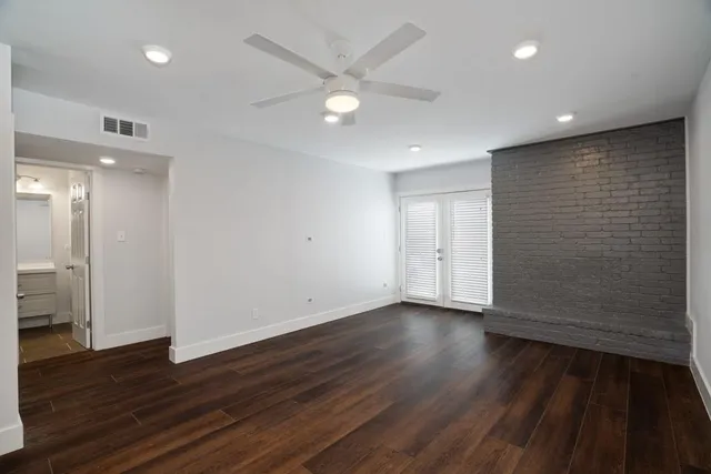 an empty room with wooden floor and a ceiling fan