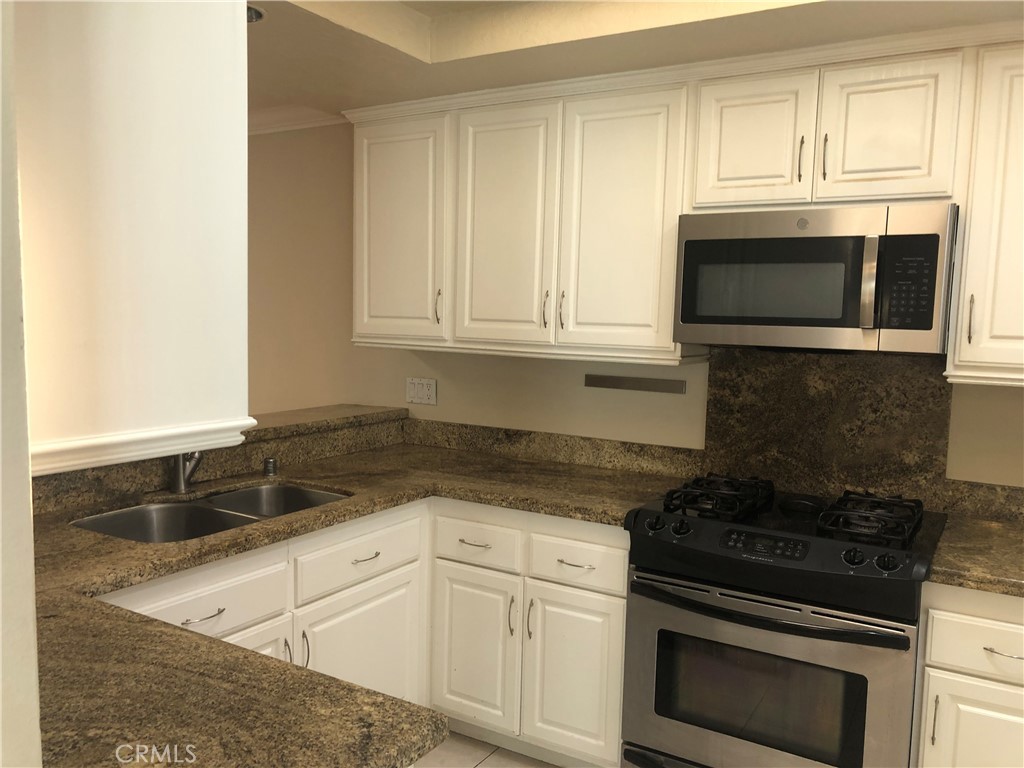 65 Orchard Irvine, CA 92618 - Photo 4 of 21 a kitchen with granite countertop white cabinets and black appliances