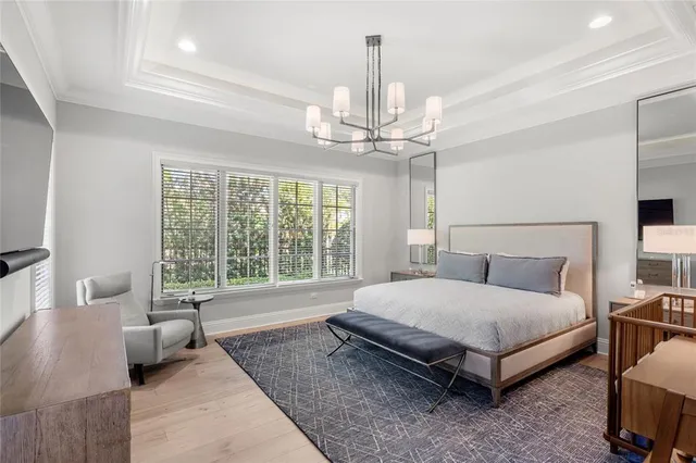 a spacious bedroom with a bed a couch and a chandelier