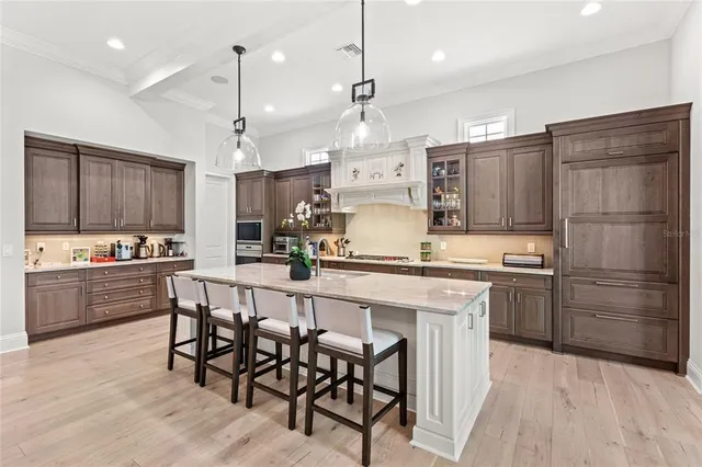 a kitchen with stainless steel appliances kitchen island granite countertop a table chairs and a refrigerator