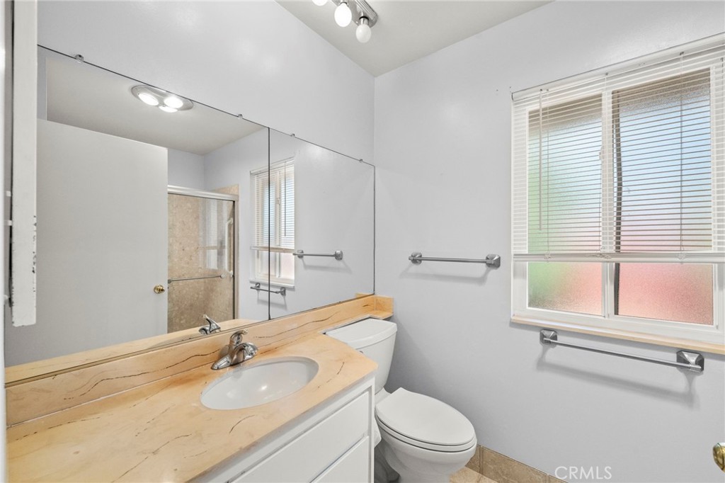 25915 Roanoke Road Menifee, CA 92586 - Photo 31 of 58 a bathroom with a granite countertop sink toilet a mirror and shower