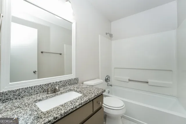 a bathroom with a granite countertop sink a toilet and a mirror