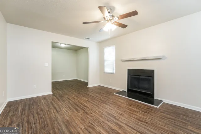 a view of an empty room with wooden floor and a fireplace