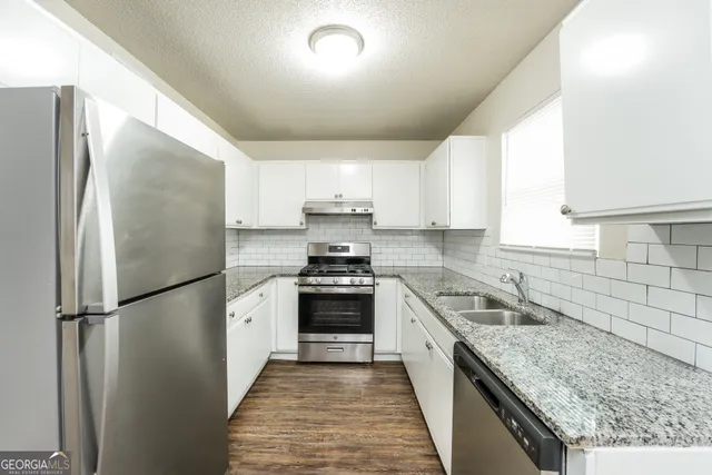 a kitchen with a refrigerator a sink and wooden cabinets