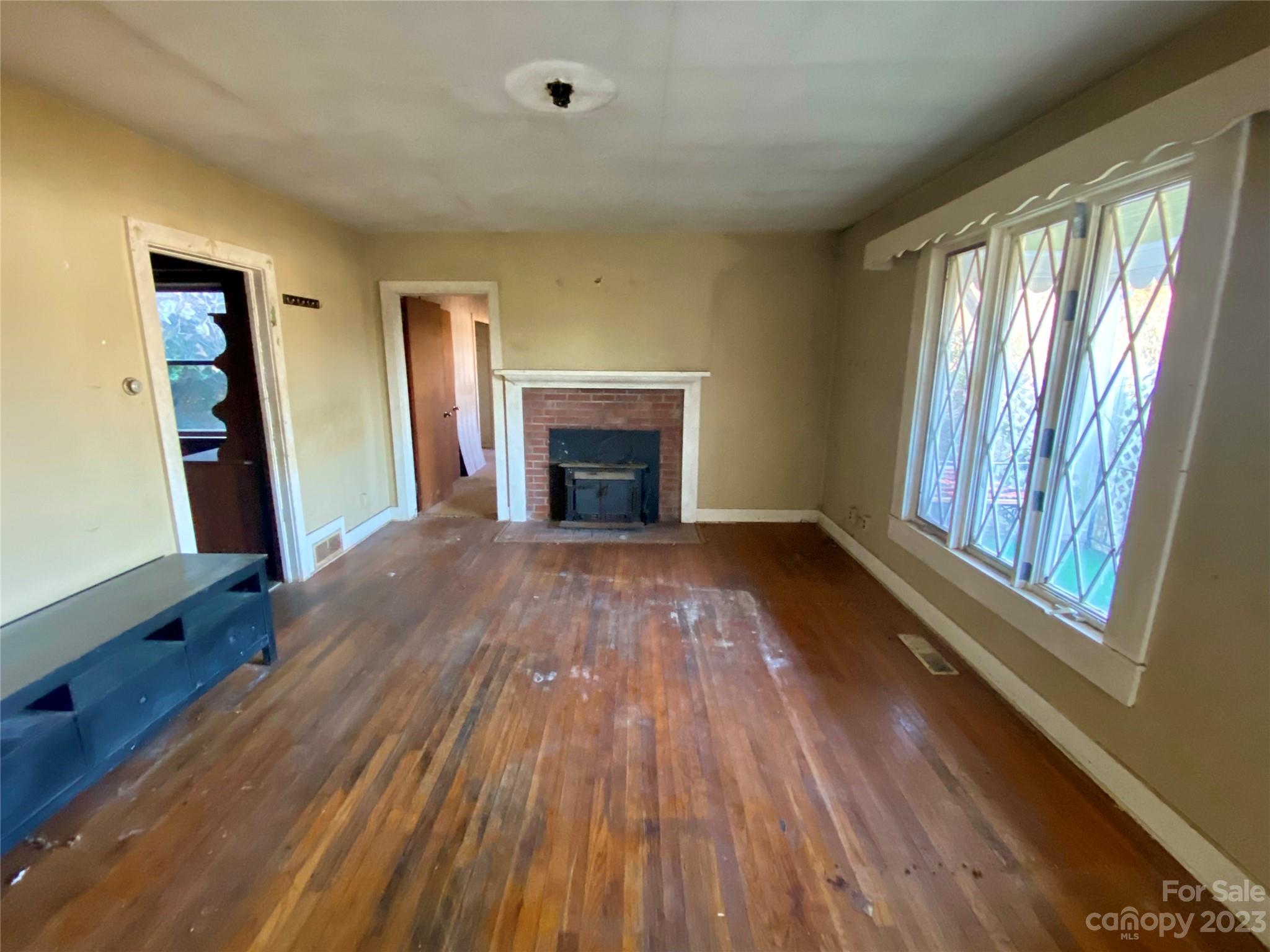 793 Silver Creek Road Mill Spring, NC 28756 - Photo 13 of 20 wooden floor fireplace and windows in an empty room