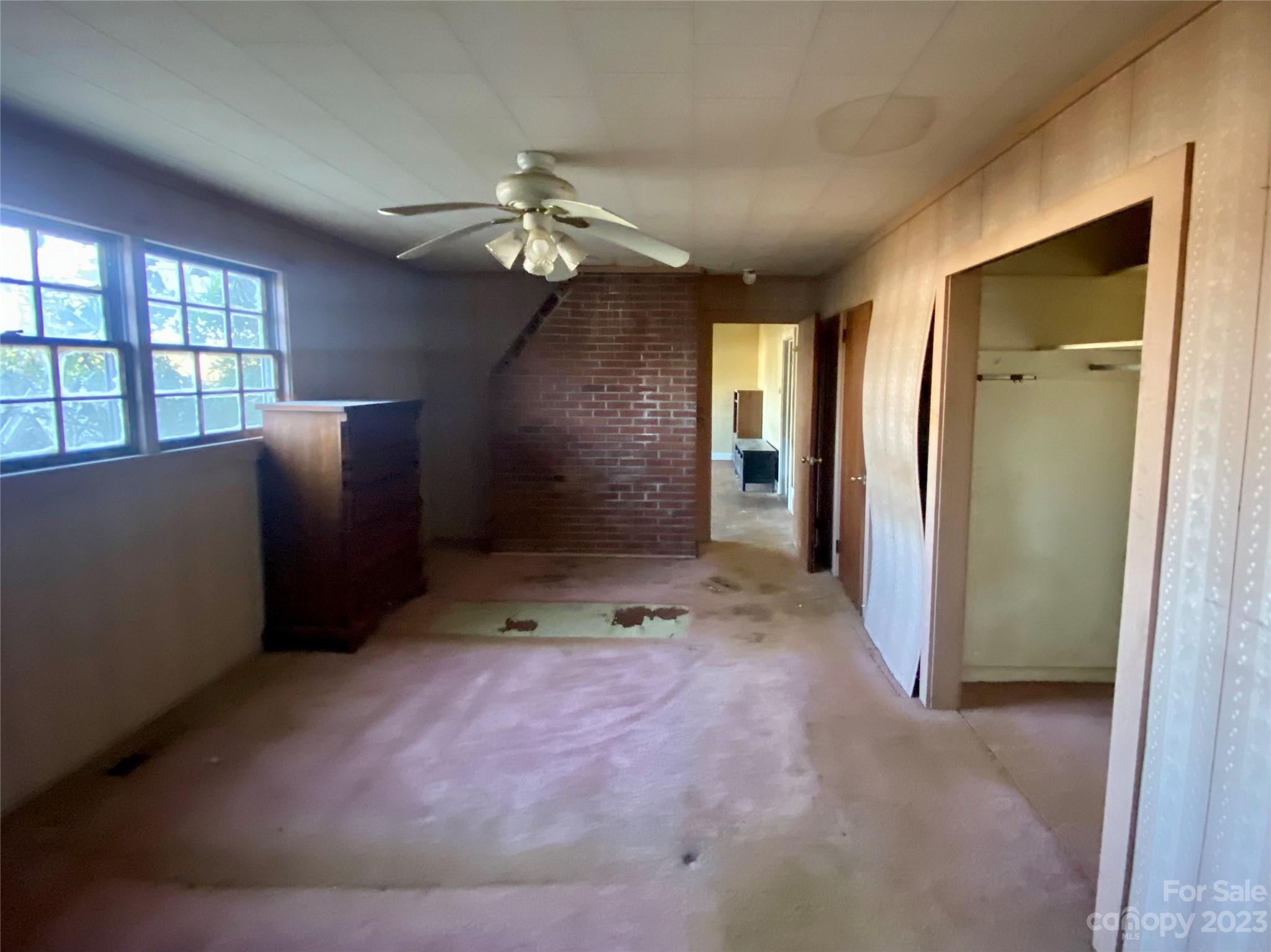 793 Silver Creek Road Mill Spring, NC 28756 - Photo 14 of 20 en empty room with windows and ceiling fan
