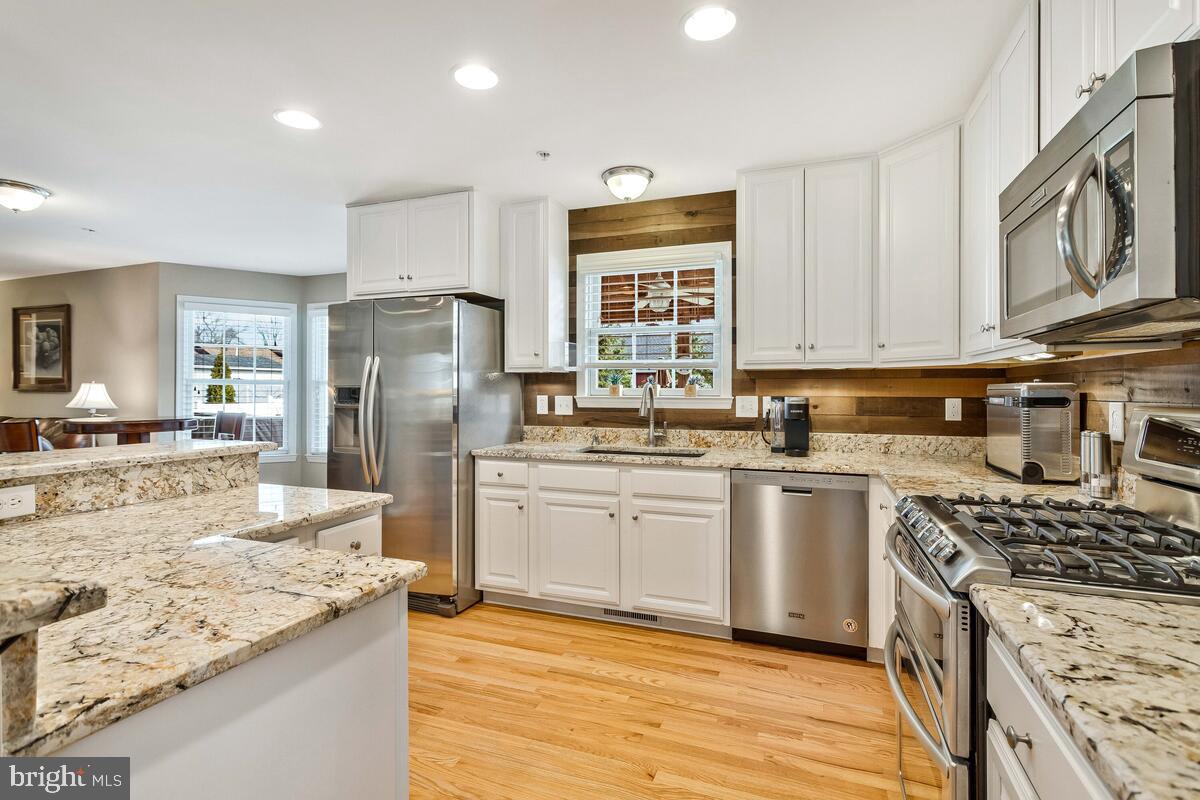 1713 Shore Drive Edgewater, MD 21037 - Photo 10 of 44 a kitchen with stainless steel appliances granite countertop a stove top oven a refrigerator a sink and dishwasher with wooden floor