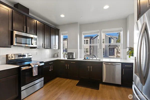 a kitchen with stainless steel appliances granite countertop a stove a sink and a microwave