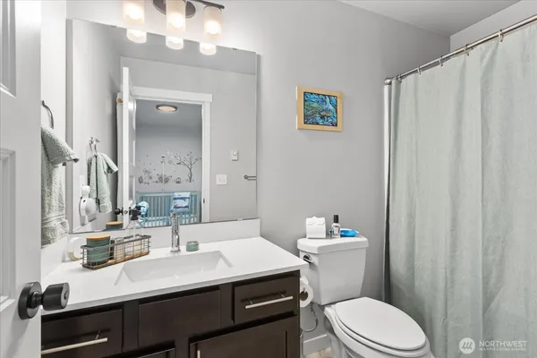 a bathroom with a sink a toilet a mirror and shower curtain