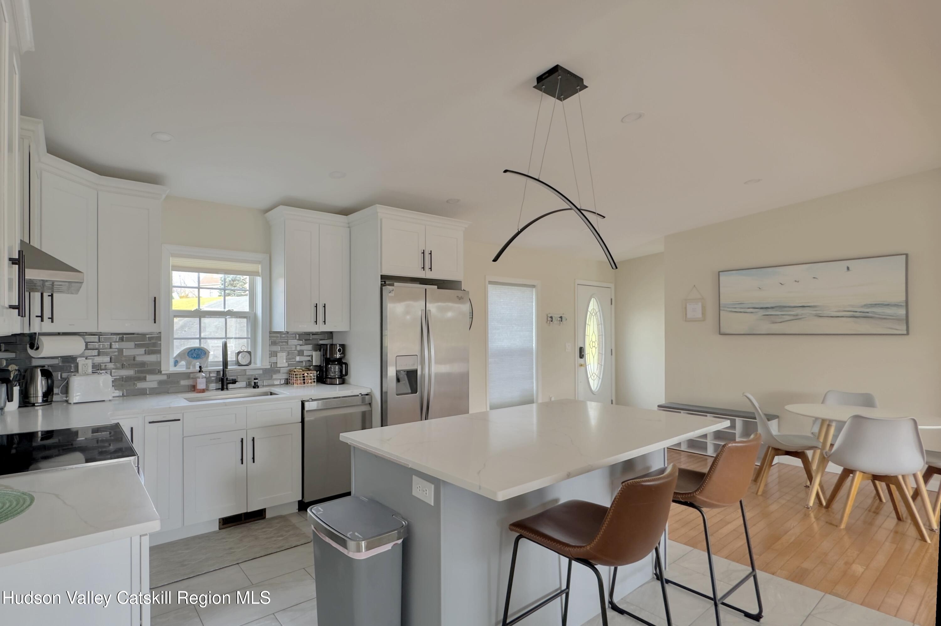70 Travis Place Athens, NY 12015 - Photo 9 of 57 a kitchen with stainless steel appliances kitchen island a table chairs in it and white cabinets