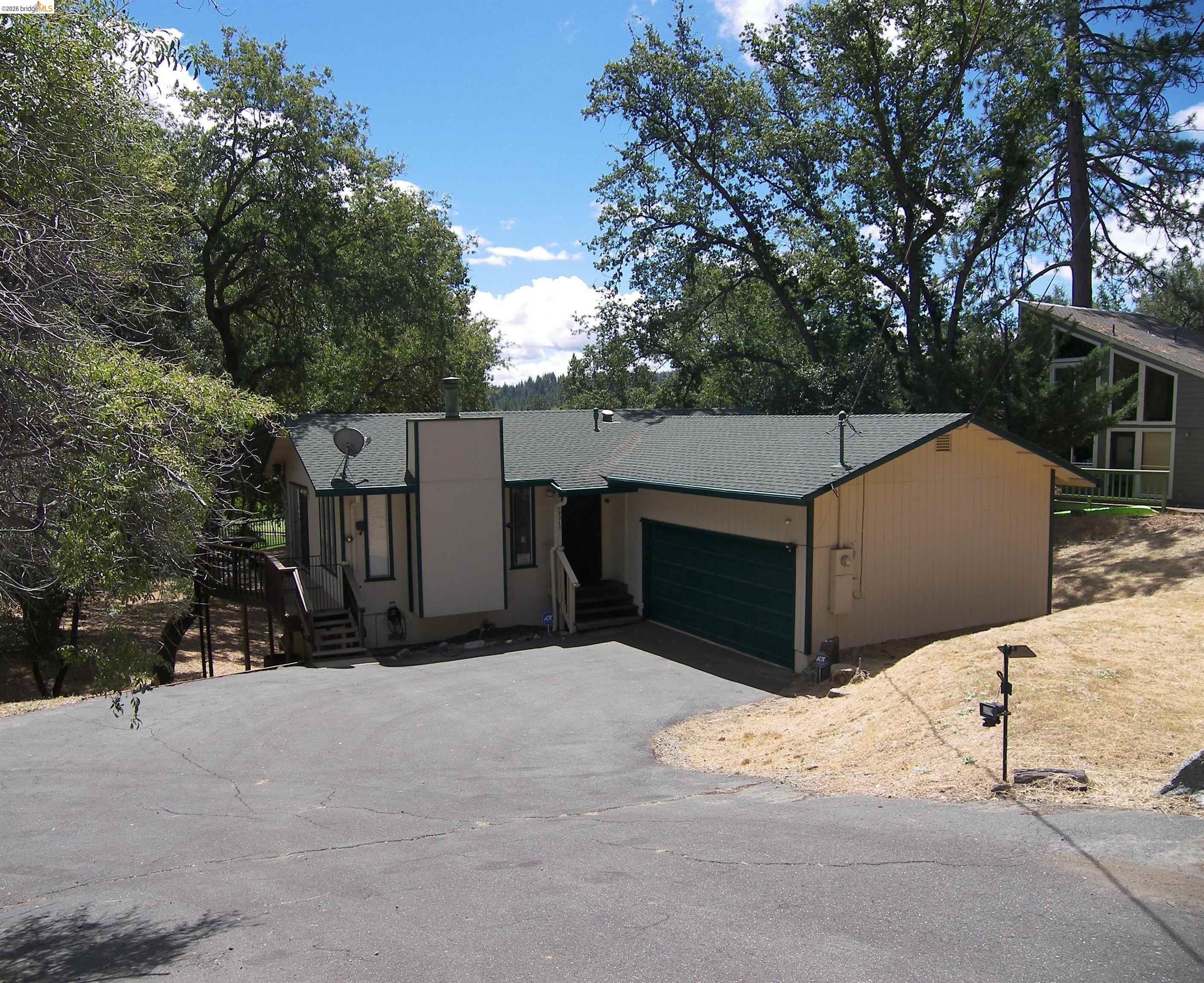 19215 Ferretti Road Groveland, CA 95321 - Photo 1 of 40 Single-story residence featuring a green shingle roof, attached garage with a green door, and light-colored siding
