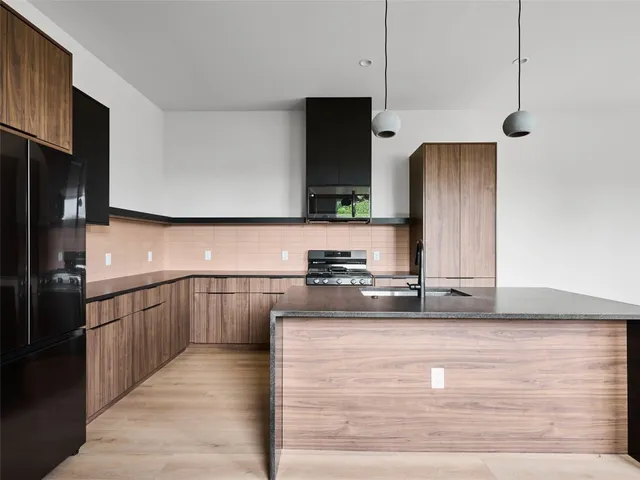 a kitchen with stainless steel appliances granite countertop a sink a stove and refrigerator