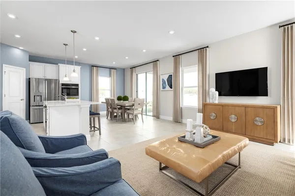 a living room with furniture a flat screen tv and kitchen view