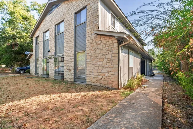 a view of a house with a dirt yard and a large tree