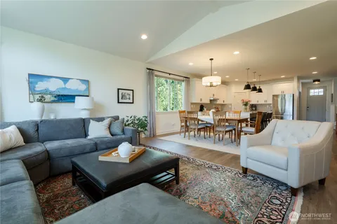 a kitchen with stainless steel appliances granite countertop a refrigerator a sink dishwasher a stove and white cabinets with wooden floor