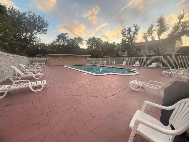 a view of a backyard with table and chairs plants and wooden fence