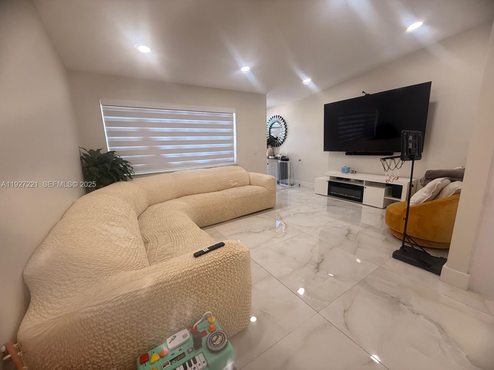 6864 Northwest 166th Terrace, Unit 903 Miami Lakes, FL 33014 - Photo 3 of 29 a living room with furniture and a flat screen tv