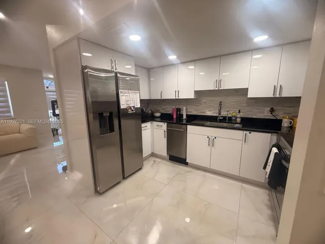 a kitchen with stainless steel appliances granite countertop a sink a stove a refrigerator and cabinets