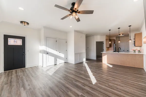 wooden floor in an empty room with a window and a kitchen