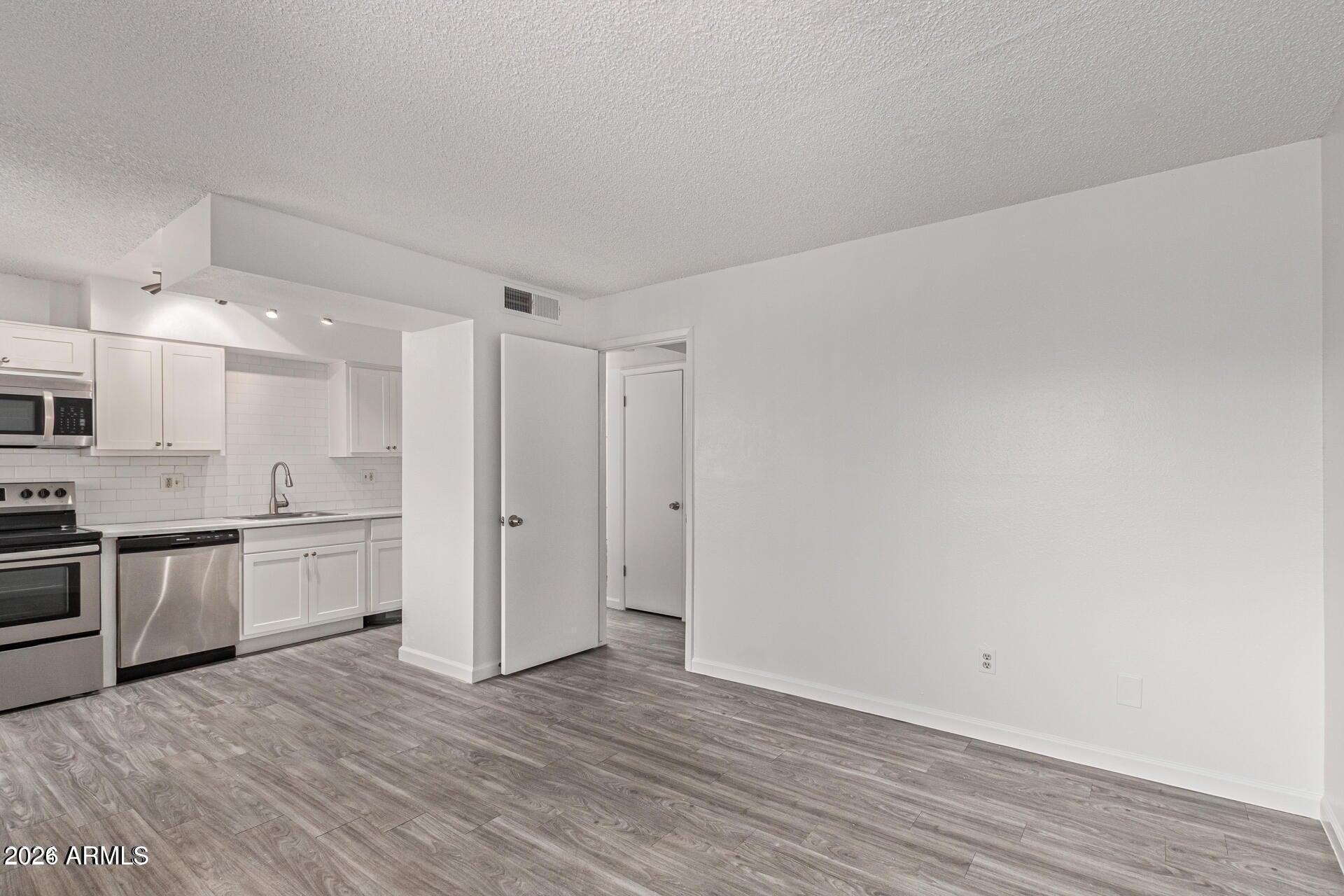1029 South Wilson Street, Unit 14 Tempe, AZ 85281 - Photo 3 of 12 a large kitchen with a wooden floor and stainless steel appliances