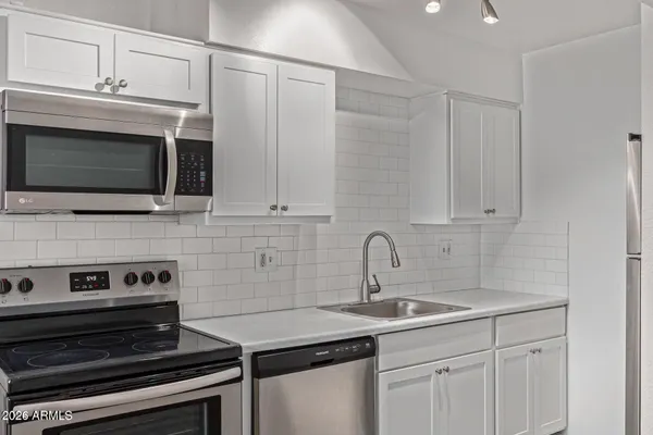 a kitchen with stainless steel appliances a sink stove and white cabinets