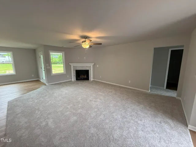 an empty room with windows and fireplace