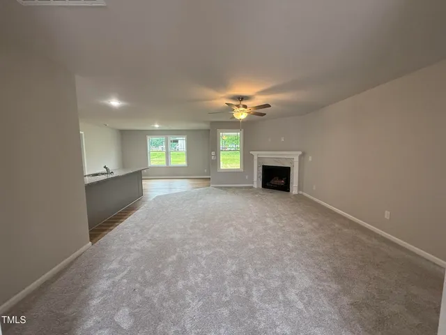 an empty room with a fireplace and chandelier fan