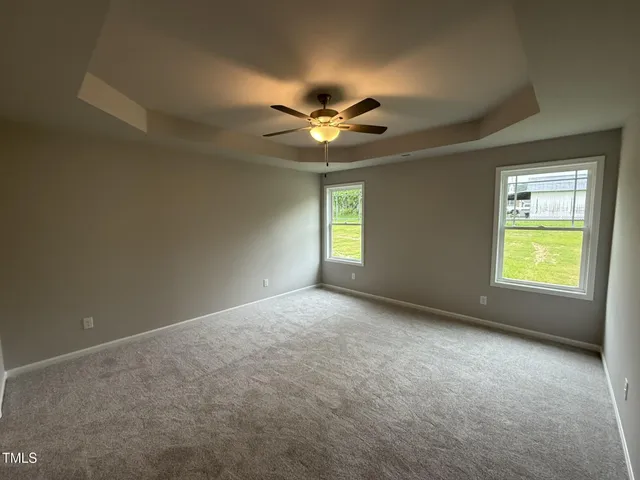 an empty room with windows and fan