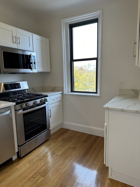 29 Bay State Road, Unit 3 Boston, MA 02215 - Photo 8 of 22 a kitchen with granite countertop a stove a sink and a microwave